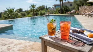 Clear acrylic wine glasses for pool lounging, resting safely on a wooden deck next to turquoise water.